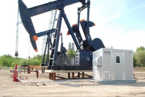 Oil pumpjack operating at a well site with surface equipment and control unit, representing oil well production optimization to improve output and efficiency.
